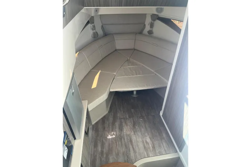  Yacht Photos Pics 2026 Sea Ray Sundancer 320 Outboard cabin interior with beige seating and wood flooring.