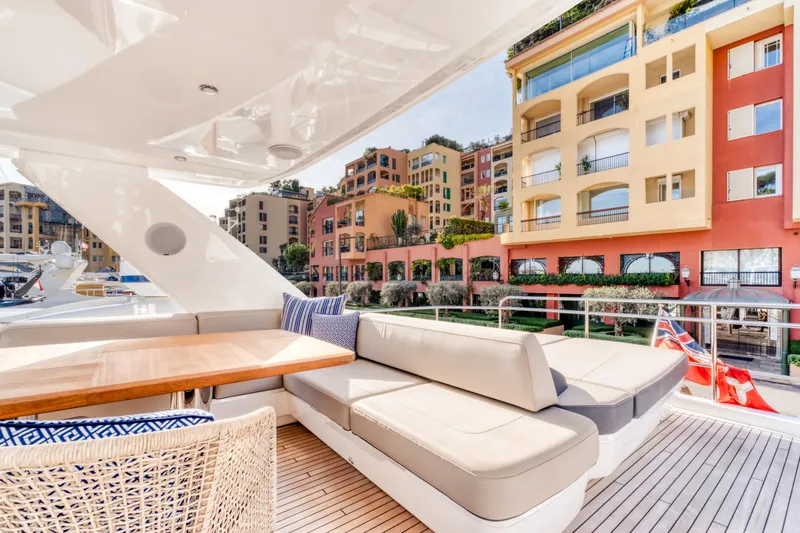  Yacht Photos Pics Luxurious 2016 Princess 68 yacht deck with elegant seating, docked near colorful waterfront buildings.