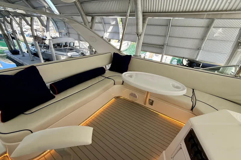 Pier Pressure Yacht Photos Pics 1999 Bayliner 3788 Command Bridge Motoryacht interior with seating and table, under a covered dock.