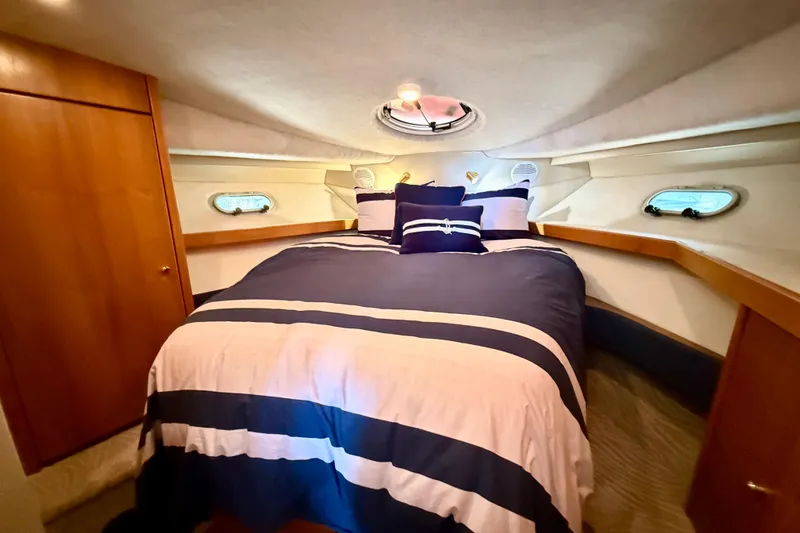 Pier Pressure Yacht Photos Pics 1999 Bayliner 3788 Command Bridge Motoryacht bedroom with striped bedding and porthole windows.