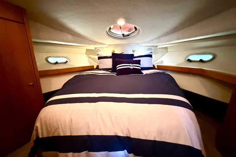 Pier Pressure Yacht Photos Pics 1999 Bayliner 3788 Command Bridge Motoryacht bedroom with striped bedding and porthole windows.