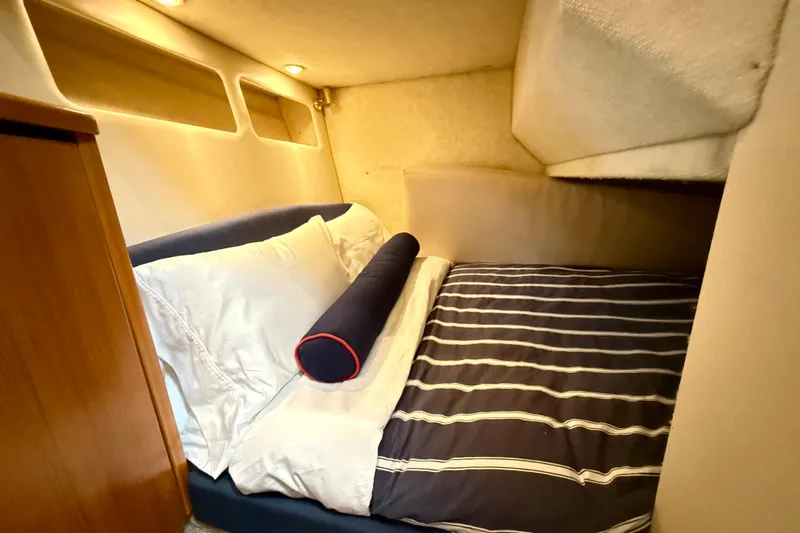 Pier Pressure Yacht Photos Pics Cozy bedroom in 1999 Bayliner 3788 Command Bridge Motoryacht with striped bedding and soft lighting.