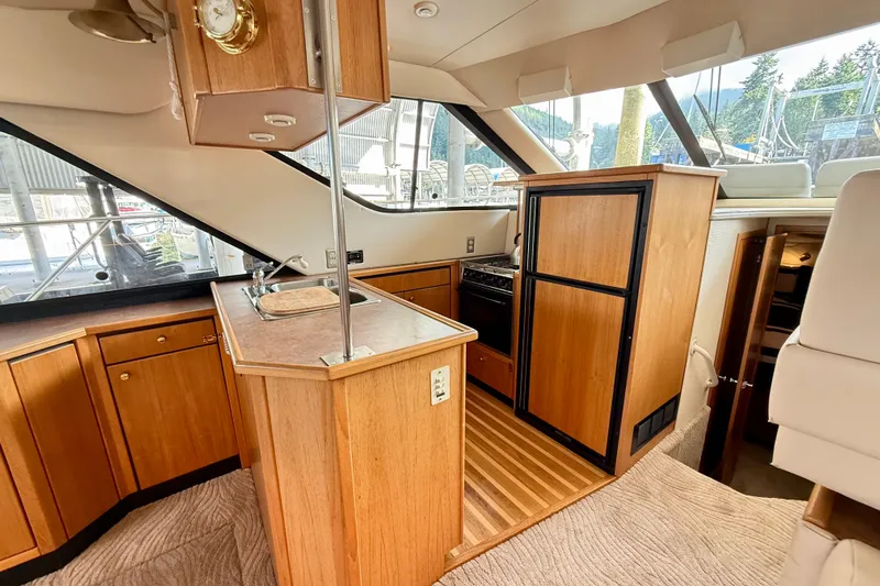 Pier Pressure Yacht Photos Pics 1999 Bayliner 3788 Command Bridge Motoryacht interior with wood cabinetry and kitchen area.
