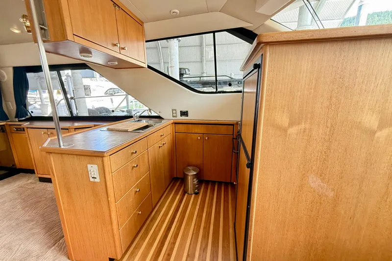 Pier Pressure Yacht Photos Pics 1999 Bayliner 3788 Command Bridge Motoryacht interior kitchen with wood cabinetry and flooring.