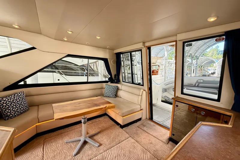 Pier Pressure Yacht Photos Pics Luxurious interior of 1999 Bayliner 3788 Command Bridge Motoryacht with plush seating and wooden table.