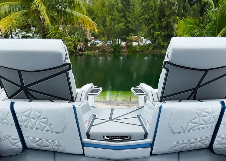  Yacht Photos Pics 2025 Nautique G23 Paragon boat seats overlooking a serene lake with lush greenery.