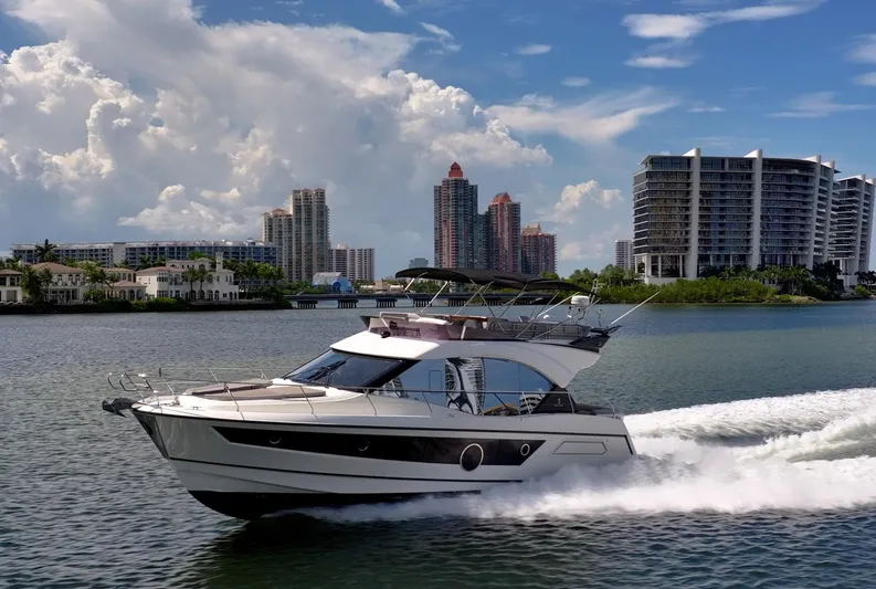 Kedem Plus Yacht Photos Pics 2021 Beneteau Monte Carlo 52 yacht cruising near modern city skyline.