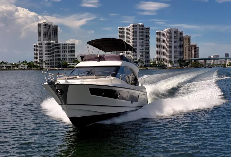 Kedem Plus Yacht Photos Pics 2021 Beneteau Monte Carlo 52 yacht cruising near city skyline on a sunny day.