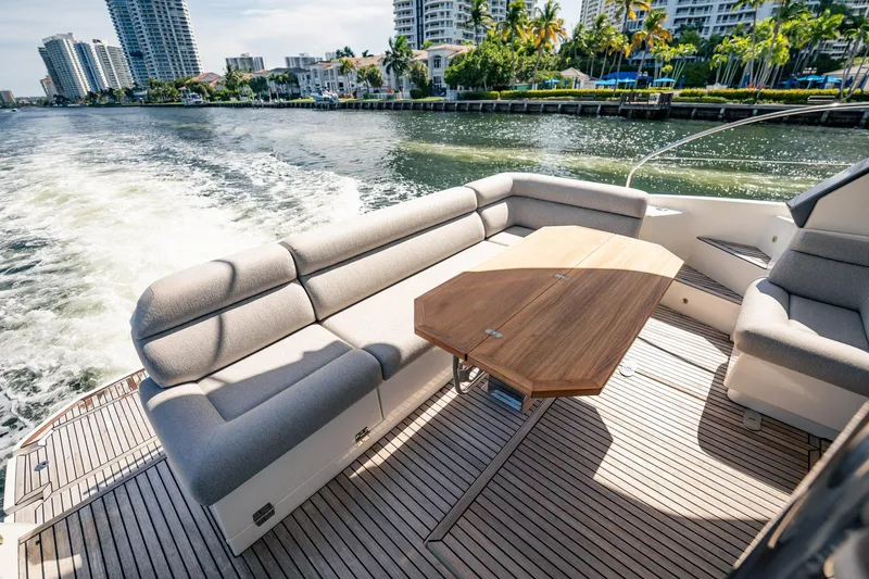 Kedem Plus Yacht Photos Pics Luxurious seating area on 2021 Beneteau Monte Carlo 52 yacht, cruising near waterfront cityscape.
