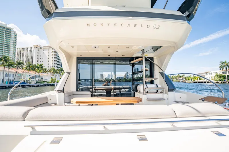 Kedem Plus Yacht Photos Pics 2021 Beneteau Monte Carlo 52 yacht with luxurious deck, cityscape background, and waterfront view.