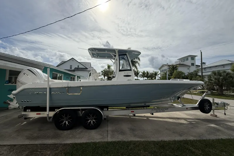  Yacht Photos Pics 2025 Sea Hunt Escape 28 boat on trailer, parked in residential area under cloudy sky.