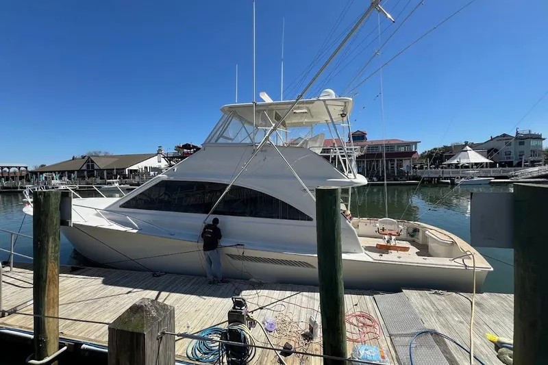 Reel Interest Yacht Photos Pics 2002 Ocean Yachts 56 Super Sport docked at a marina under clear blue skies.