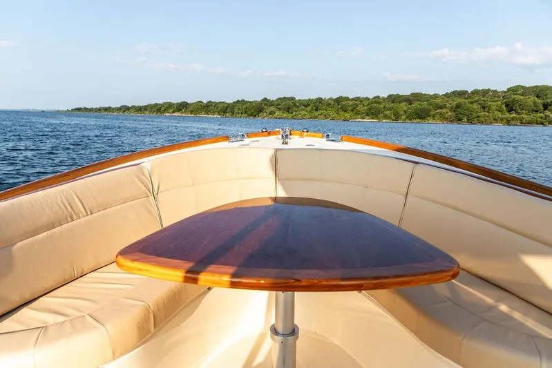 Cheetah Yacht Photos Pics Hinckley T29 CC 2014 boat interior with cushioned seating and wooden table on calm water.