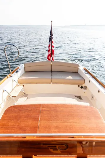 Cheetah Yacht Photos Pics Hinckley T29 CC 2014 boat with American flag, wooden deck, and cushioned seating on open water.