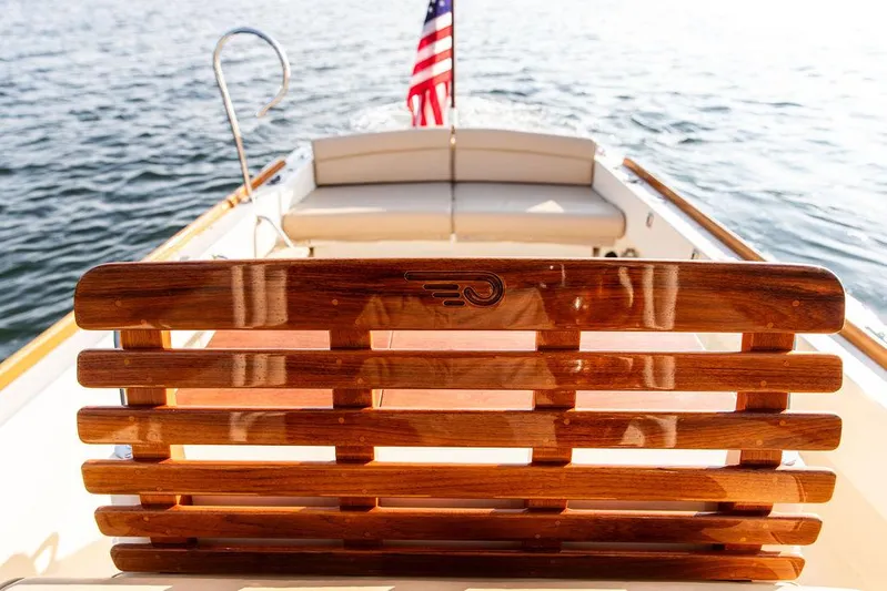 Cheetah Yacht Photos Pics Hinckley T29 CC 2014 boat with wooden seating and American flag on calm water.