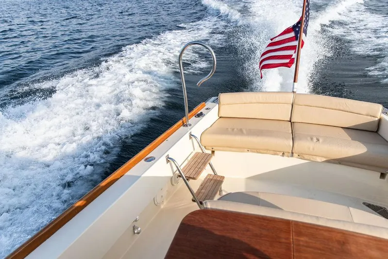 Cheetah Yacht Photos Pics 2014 Hinckley T29 CC boat cruising with American flag, beige seating, and ocean wake.