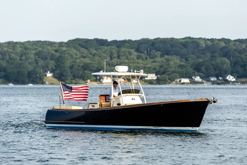 Cheetah Yacht Photos Pics 2014 Hinckley T29 CC boat on water with American flag, forested shoreline in background.