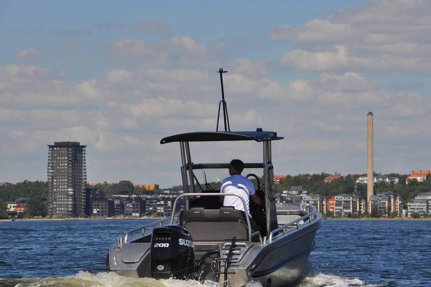 2024 Arronet 20 5 SPT boat cruising on a lake with cityscape background.