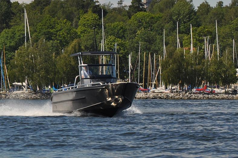 2024 Arronet 20 5 SPT boat cruising on a lake with lush green trees.