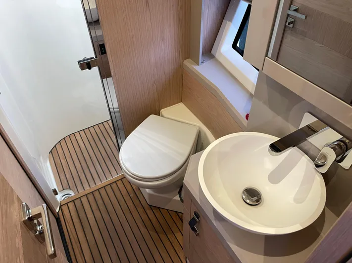  Yacht Photos Pics 2022 Beneteau Monte Carlo 52 bathroom with modern sink, toilet, and wooden flooring.