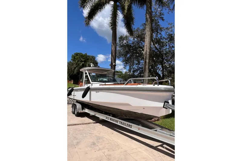  Yacht Photos Pics 2024 Axopar 28TT boat on trailer, surrounded by palm trees and blue sky.