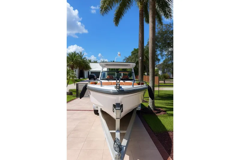  Yacht Photos Pics 2024 Axopar 28TT boat on trailer, parked under palm trees, sunny day.