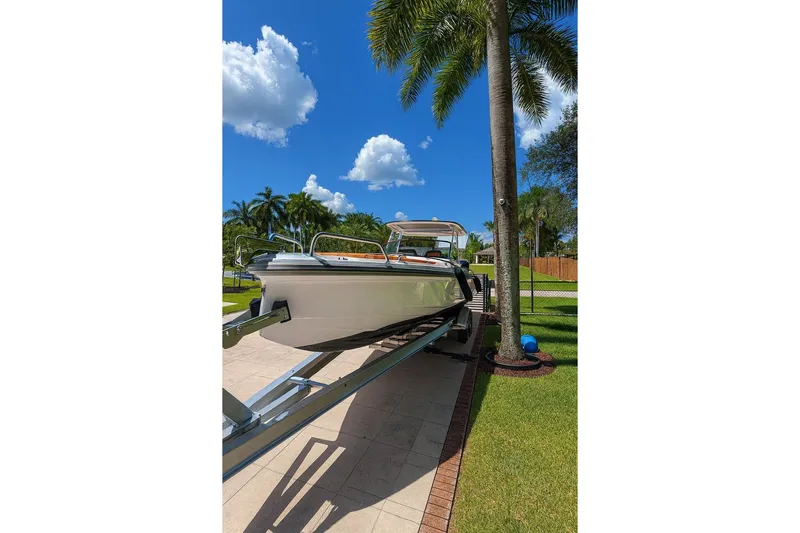  Yacht Photos Pics 2024 Axopar 28TT boat on trailer, surrounded by palm trees and blue sky.