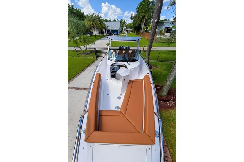  Yacht Photos Pics 2024 Axopar 28TT boat with brown seating, docked in a lush, green setting.