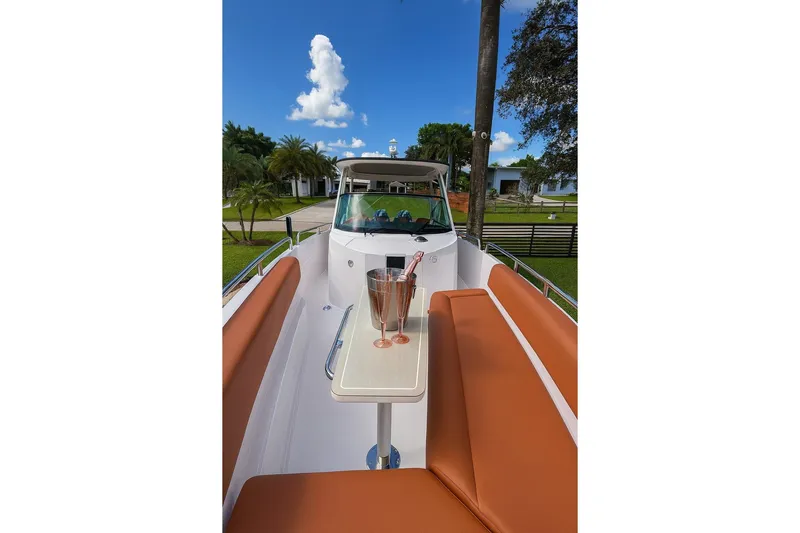  Yacht Photos Pics 2024 Axopar 28TT boat with brown seating and a table, under a clear blue sky.