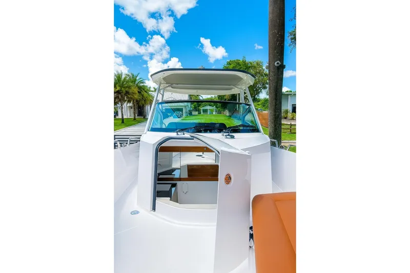  Yacht Photos Pics 2024 Axopar 28TT boat with open cabin door, showcasing sleek design under blue sky.