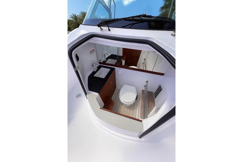  Yacht Photos Pics 2024 Axopar 28TT boat interior with compact bathroom, featuring toilet and sink.