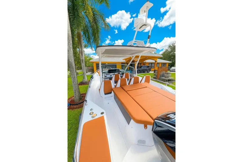  Yacht Photos Pics 2024 Axopar 28TT boat with orange seating, parked outdoors under a clear blue sky.