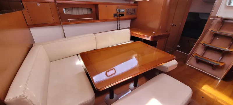 Latika Yacht Photos Pics Interior of 2011 Beneteau Oceanis 43 yacht with wooden table and cream seating.