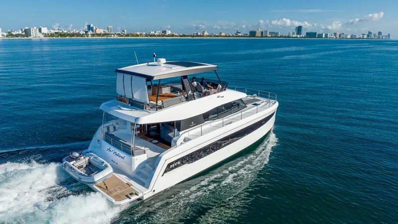 Au Natural Yacht Photos Pics 2023 Fountaine Pajot MY 6 yacht cruising near a city skyline.