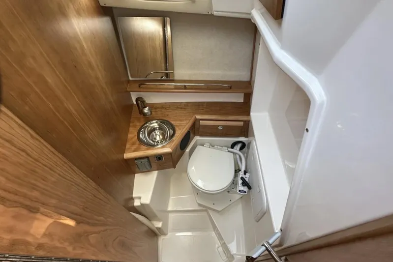  Yacht Photos Pics 2026 Cutwater C-248 Coupe bathroom with compact sink, toilet, and wooden accents.