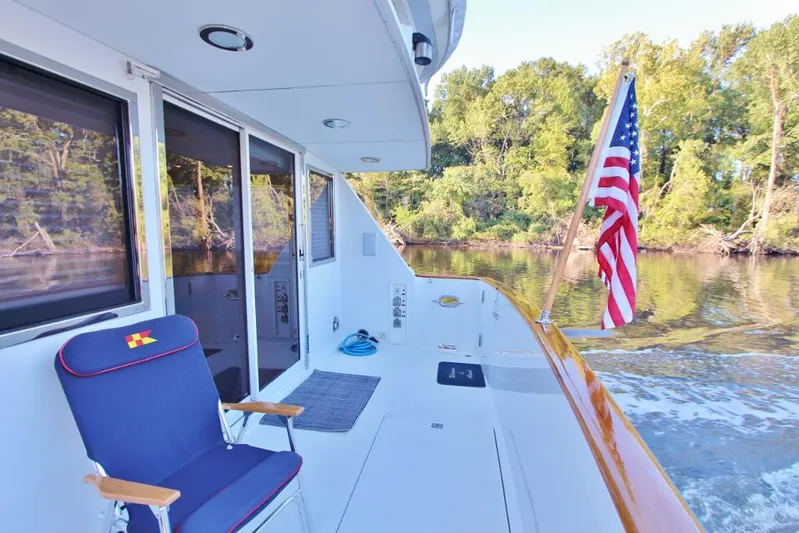 Slainte Yacht Photos Pics 1992 Tollycraft 53 Motor Yacht deck with American flag and chair, cruising on a calm river.