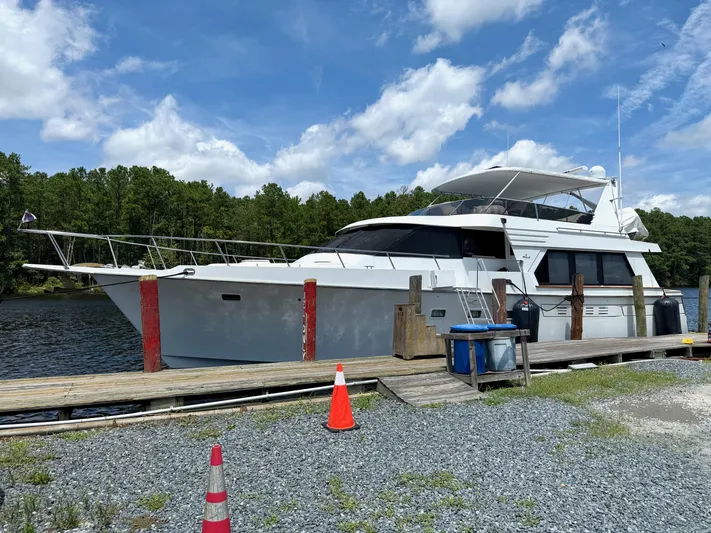 Slainte Yacht Photos Pics 1992 Tollycraft 53 Motor Yacht docked by a serene lake under a blue sky.