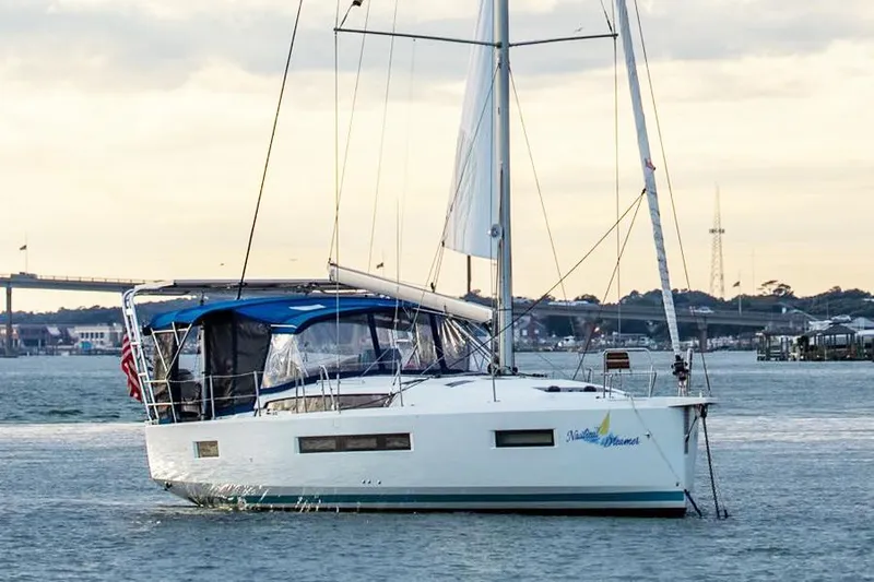 Nautical Dreamer Yacht Photos Pics 2019 Jeanneau Sun Odyssey 490 sailboat on calm water, with scenic background.