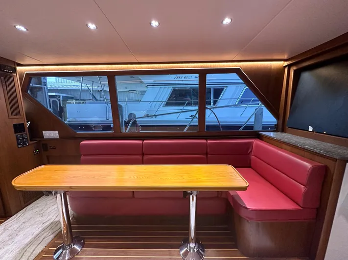 The Godfather Yacht Photos Pics Interior of 1986 Hatteras 52 Convertible yacht with red seating and wooden table.