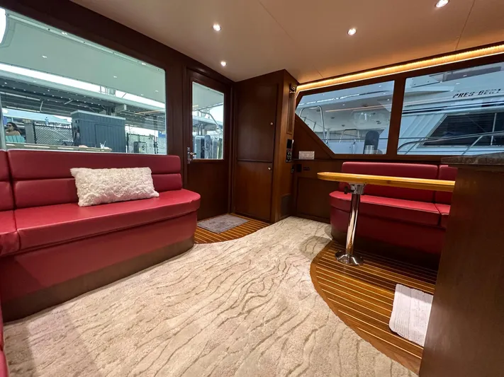 The Godfather Yacht Photos Pics Luxurious interior of 1986 Hatteras 52 Convertible yacht with red seating and wood accents.