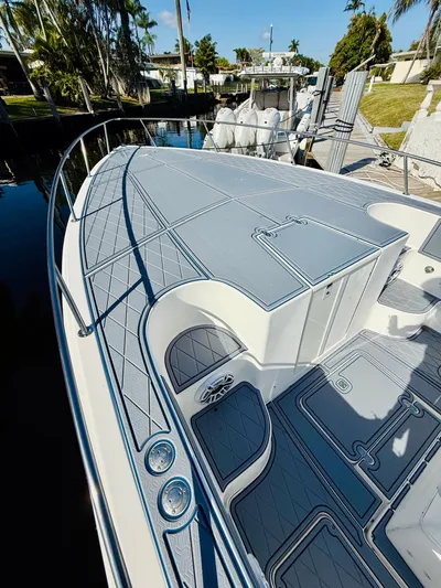  Yacht Photos Pics 2003 Fountain 38 TE boat with sleek deck design, docked near lush greenery.