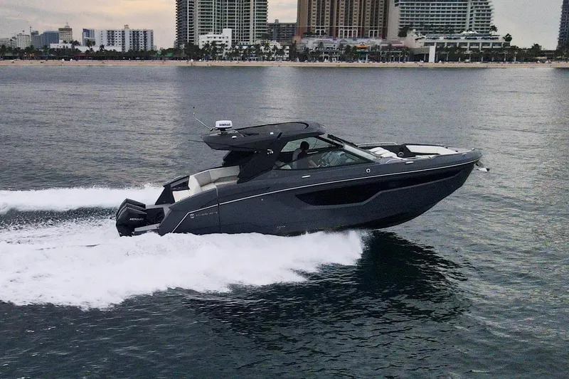 Di Blue Yacht Photos Pics 2022 Cruisers Yachts 38 GLS speeding on water with city skyline backdrop.