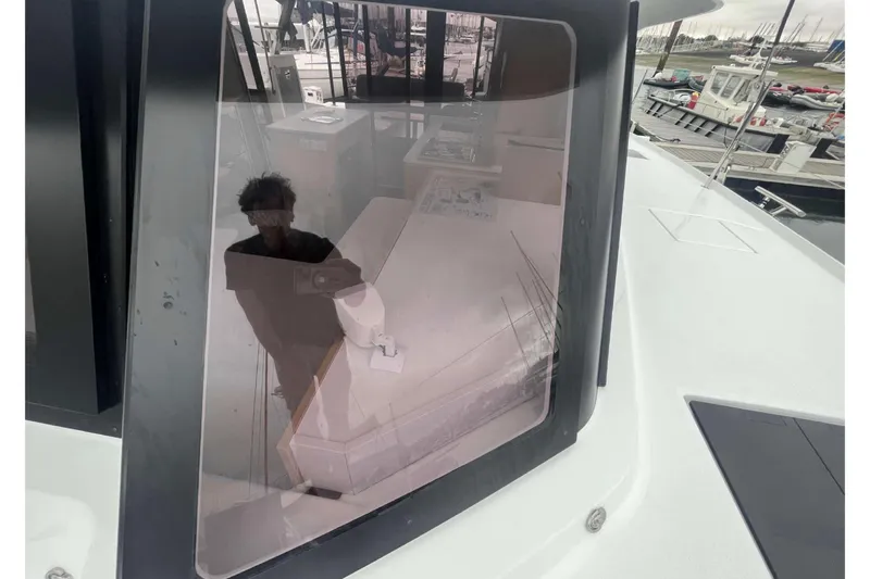 Fonn Taistil Domhain Yacht Photos Pics Reflection on Fountaine Pajot 41 yacht window, showcasing interior and marina view, 2025 model.