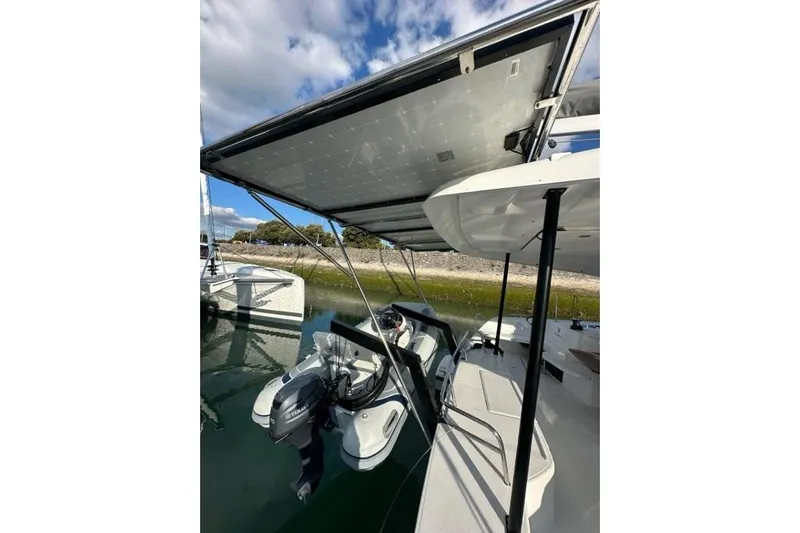 Fonn Taistil Domhain Yacht Photos Pics 2025 Fountaine Pajot 41 catamaran with solar panels and outboard motor, docked by the shore.