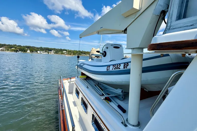 Destiny Yacht Photos Pics 1997 Sabre Sabreline 47 yacht with a small boat on deck, docked by a scenic shoreline.