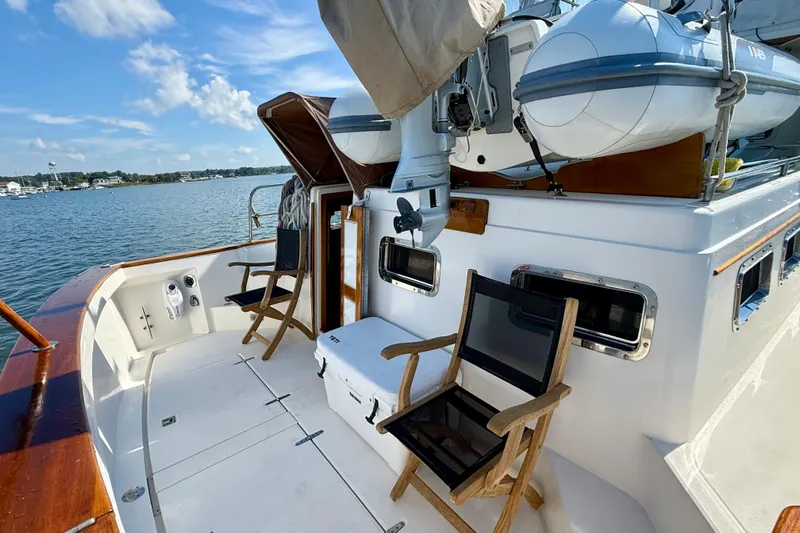 Destiny Yacht Photos Pics 1997 Sabre Sabreline 47 yacht deck with chairs, cooler, and inflatable boat, overlooking serene waters.
