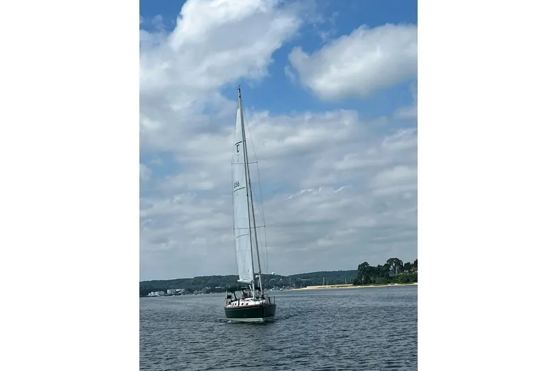 4869tw Yacht Photos Pics Sailboat Tartan 4100 (2001) cruising on a calm lake under a partly cloudy sky.