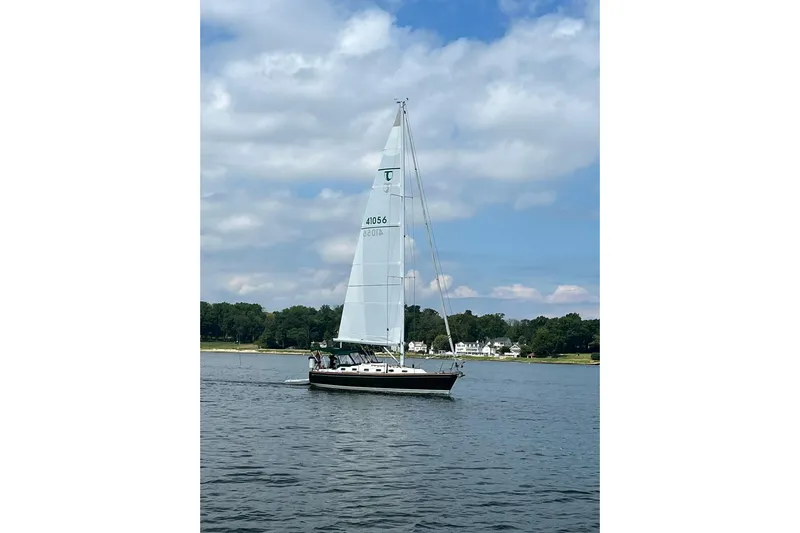4869tw Yacht Photos Pics Sailboat Tartan 4100, 2001 model, cruising on a calm lake under a partly cloudy sky.
