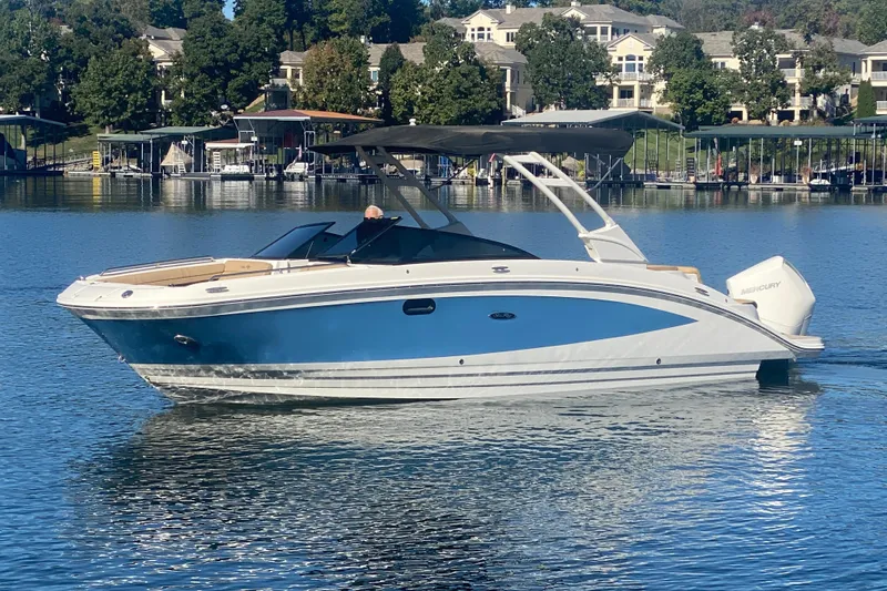  Yacht Photos Pics 2022 Sea Ray SDX 270 Outboard boat on a serene lake with docked boats.
