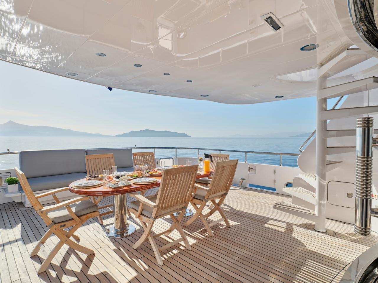 Luxurious Codecasa 115 yacht deck with dining area, ocean view, and spiral staircase, year 2000.